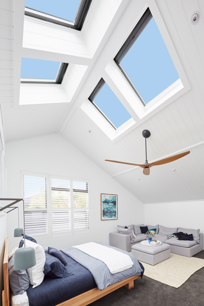 four skylights in bedroom with fan and bed with blue sheets in wellington